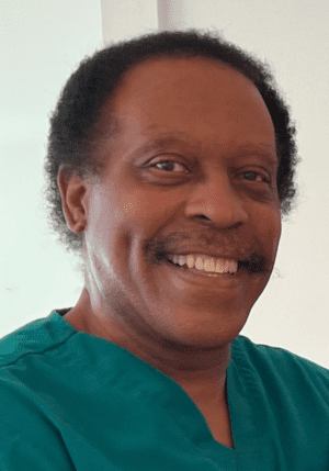 Smiling man in teal scrubs against a light background.