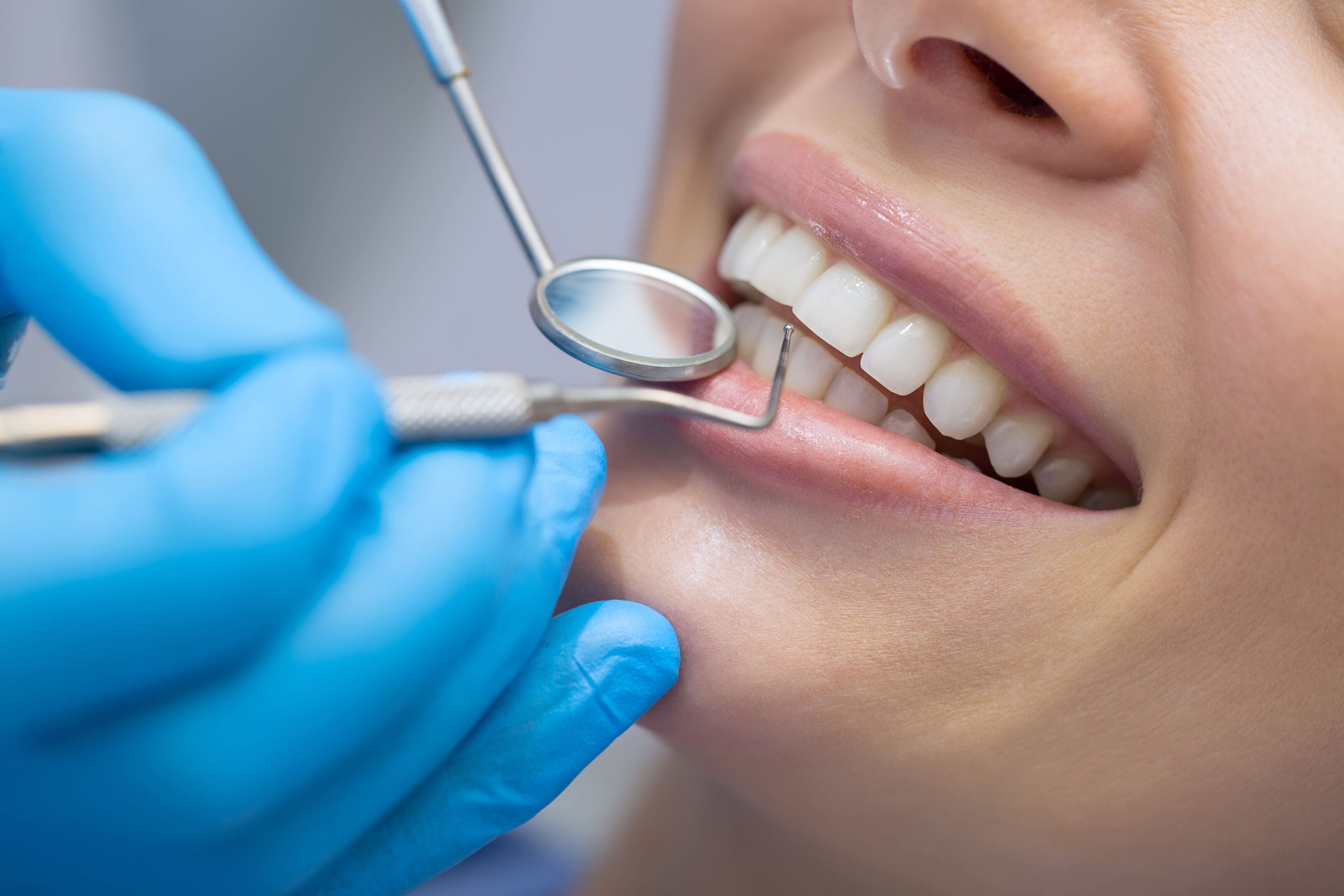 Dentist examining a patient's teeth with dental tools.