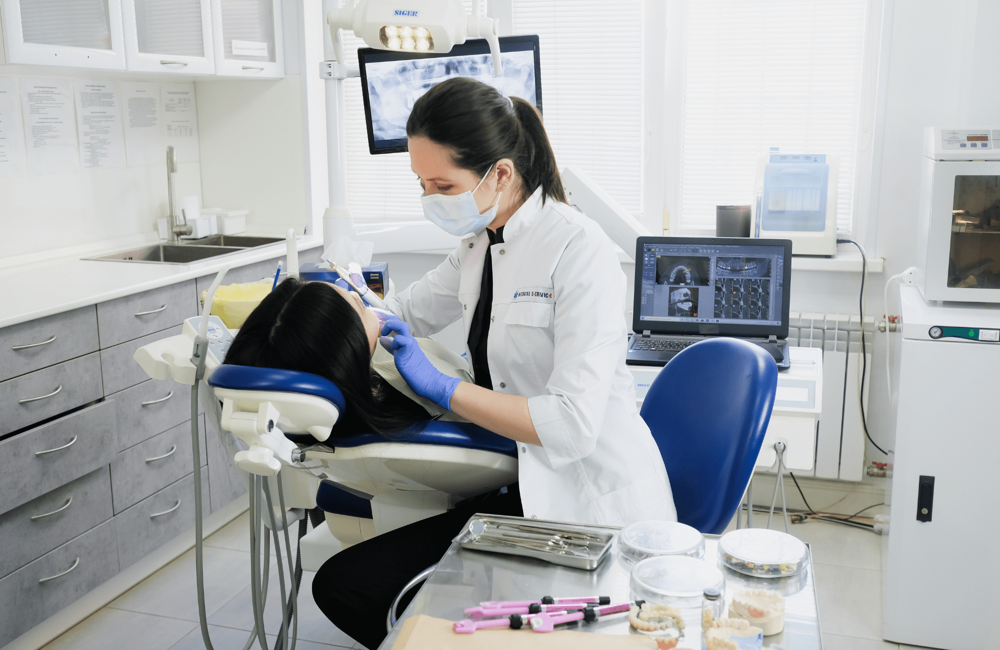 Dentist treating a patient wearing a mask and gloves.