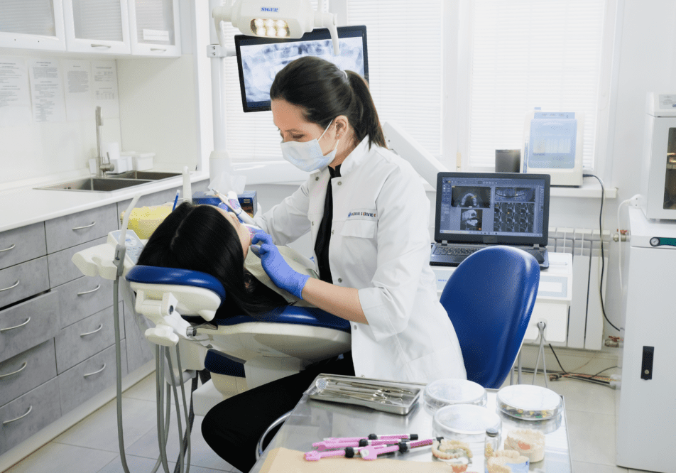 Dentist treating a patient wearing a mask and gloves.
